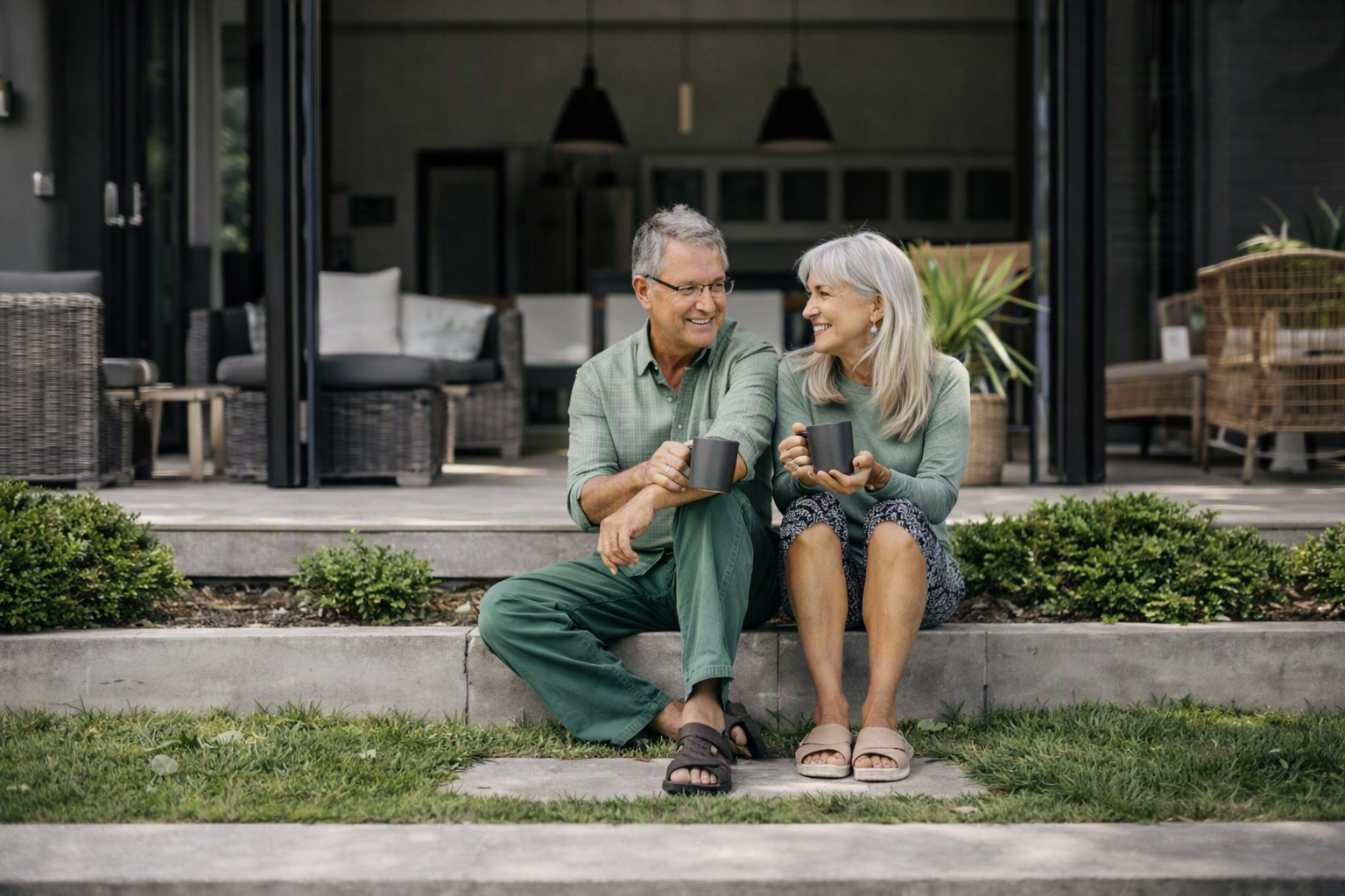 Smiling couple enjoying coffee on the patio steps of their new Colorado home
