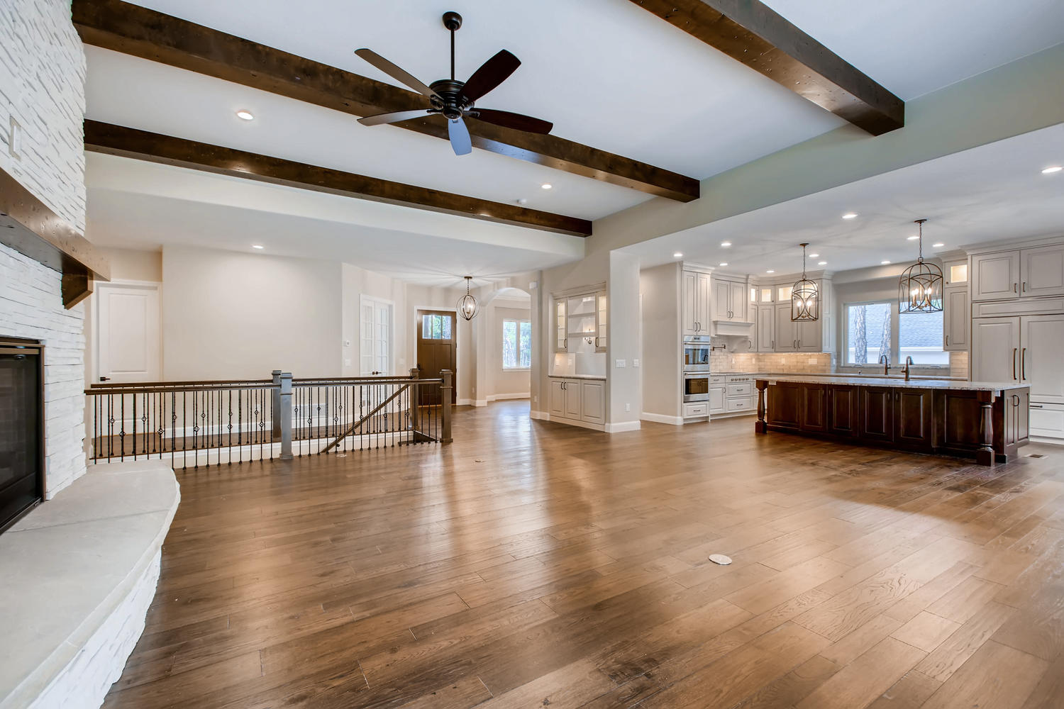 Spacious grand room with exposed wood beams, hardwood floors, and an open gourmet kitchen — showcasing Ranch Living standard craftsmanship